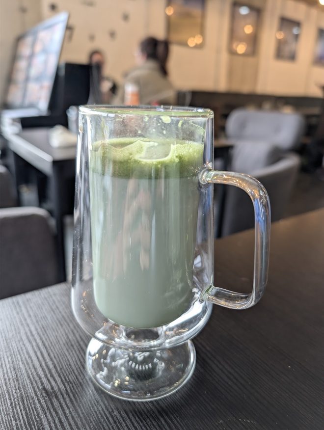A matcha latte in a tall glass mug in the cafe