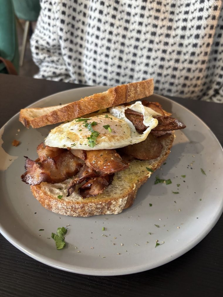 Toast topped with bacon and a fried egg on a grey plate